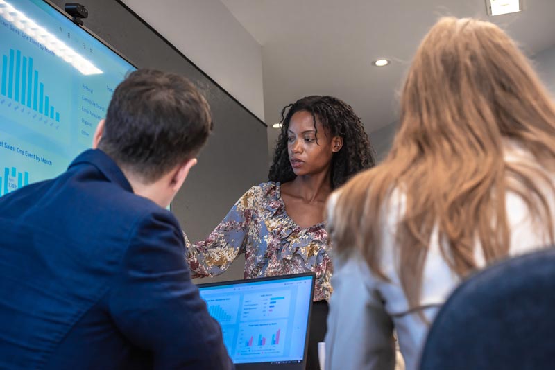Data analysis service professionals around screens examining data