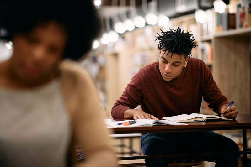 Dissertation student with open books in a university library